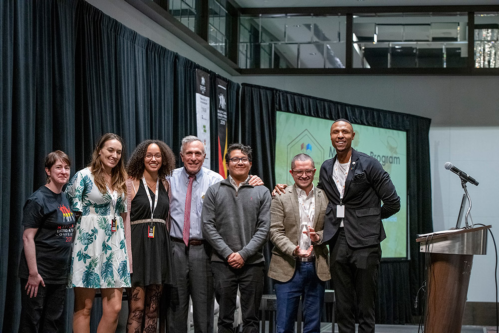 conference attendees pose for picture on stage